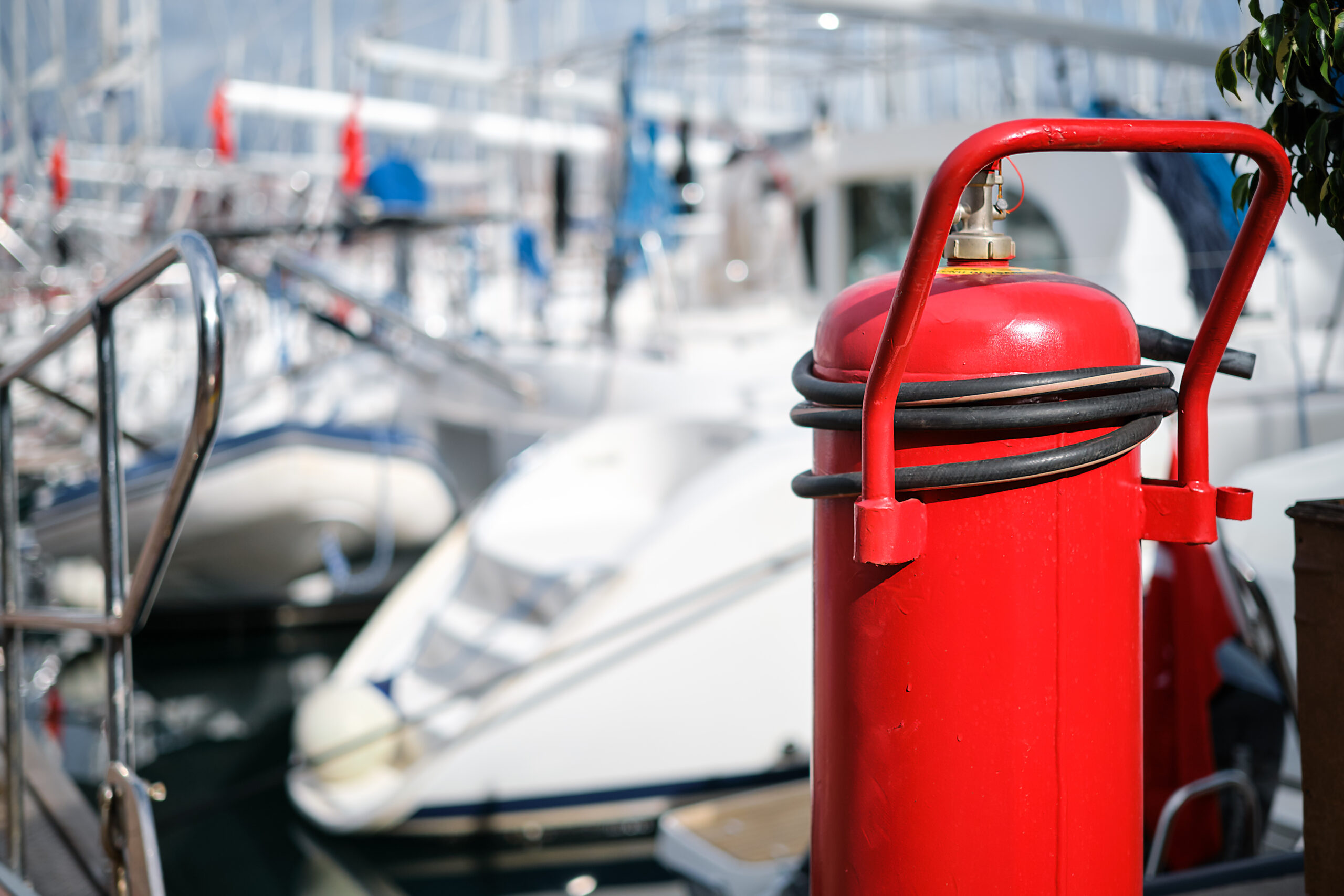 fire extinguisher close up on the mooring of the yacht club, blurred background. providing fire protection and safety prevention.