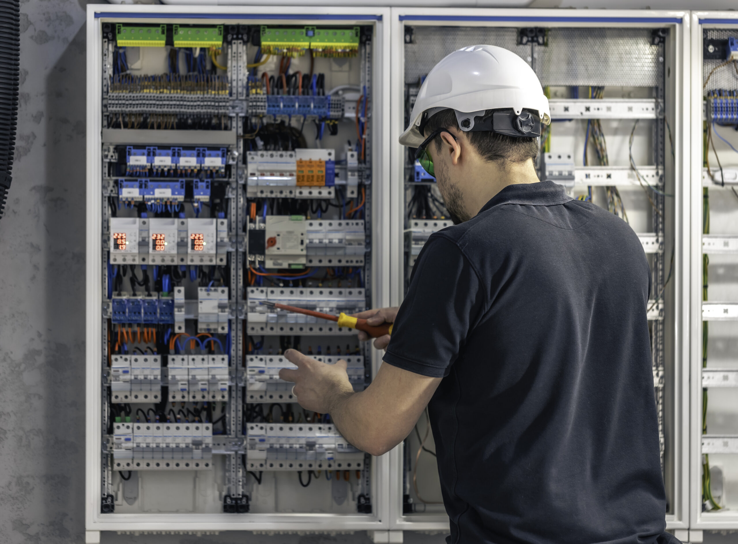 male electrician works switchboard using electrical connection cable
